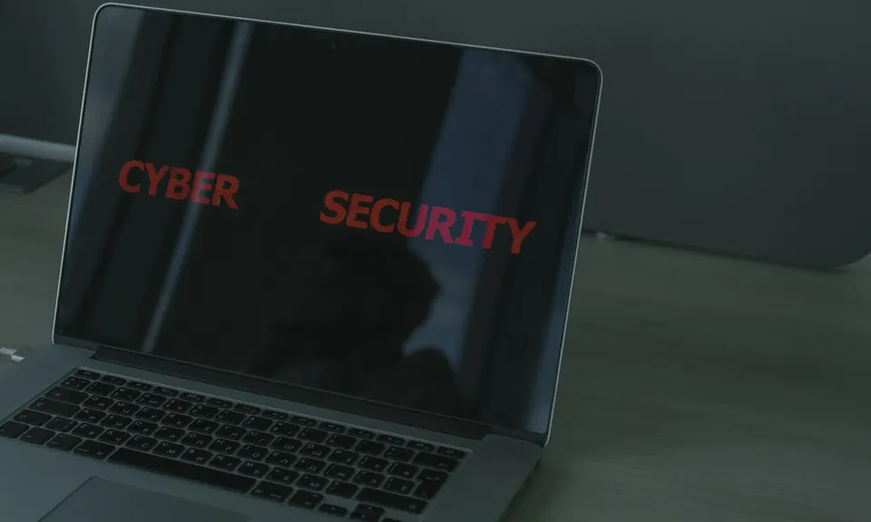 Laptop in a dark room with the words cyber security on its screen