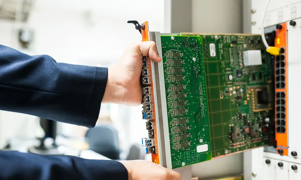 Technician fitting a circuit board into a network rack